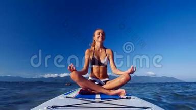 女孩坐在莲<strong>花的</strong>姿态在桨板对<strong>海洋</strong>